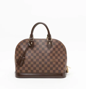 Louis Vuitton Damier Alma PM Väska - Säljer en ikonisk handväska från Louis Vuitton med klassiskt brunt och mörkbrunt rutigt mönster. Har några repor samt fläck i insidan men inte något som märks så mycket. Vid intresse kan jag skicka fler bilder videos.