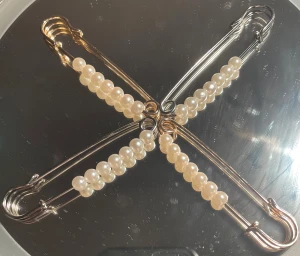 Pärlade säkerhetsnålar i guld och silver - Fyra stora säkerhetsnålar dekorerade med vita pärlor. Två nålar är i guldfärgad och två i silverfärgad. Kan användas som accessoar till kläder.