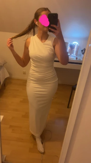 Vit långklänning, studentklänning  - Säljer en elegant vit långklänning. Klänningen har en figurnära passform och är tillverkad i ett mjukt, stretchigt material som sitter snyggt mot kroppen. Perfekt för dig som vill ha en stilren och modern look. Skulle ha till studenten emn användes ej. Nypris 400kr!