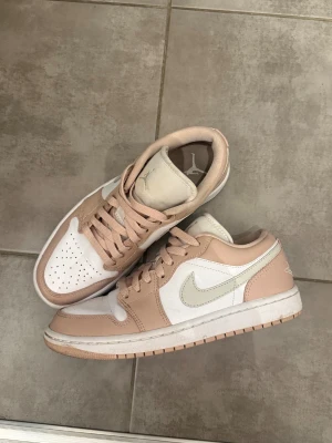 Nike Jordan 1 Low i beige och vitt - Nike Jordan 1 Low sneakers i beige och vit. Använd fåtal gånger. Storlek 38,5 