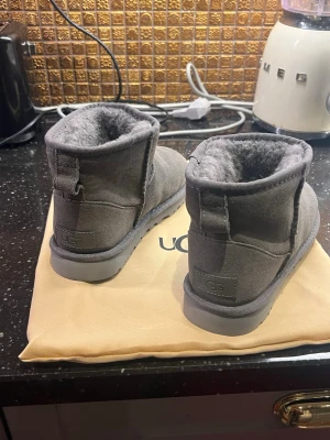Grå UGG boots med pälsfoder - Säljer ett par grå UGG boots och levereras med original dustbag från UGG. Och skorna är helt nya och oanvända!