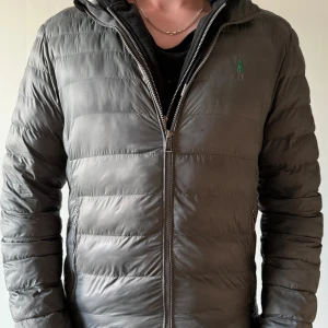 Grå/grön pufferjacka från Ralph Lauren - Polo Ralph lauren jacka som är grön/grå. Den passar personer som är runt 1,75-1,80. Den har fått ett litet hål på högra armen så har sänkt priset från 900kr till 500kr. Hör av er för frågor.