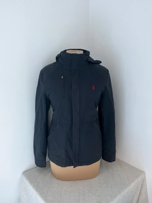 Navy vindjacka från Polo Ralph Lauren - Barnstorlek L (14-16 år) Passar båda tjej och kille storlek S💓Det går även att vika in luvan i kragen🫶 