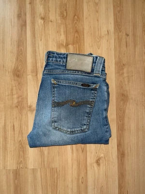 Nudie jeans   - Säljer ett par blå jeans från nudie jeans. OBS jeansea benslut är avklippta! Passformen är tight över låren och går ut längst ned. Midjan är låg. OBS jeansens modell- och storlekslapp är borta men jag bedömer dom till W30 och L30, men utgå efter måtten. Midja 33cm, längd 90cm. JAG SKICKAR EJ FLER BILDER NÄR JAG BÄR JEANSEN! storleksguide kolla måtten noggrant då jeansen alltid kan vara uppsydda heller krympta och jag tar ej emot returer :) s5,2