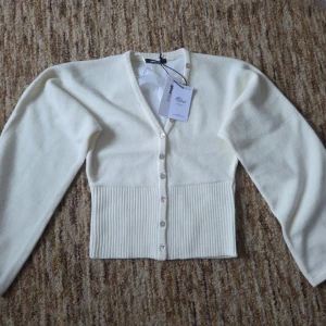 Vit ribbad kofta från Gina Tricot - Snygg vit kofta från Gina Tricot med ribbad midja och v-ringad hals, storlek S. Den är aldrig använd och har fortfarande alla lappar kvar.💗