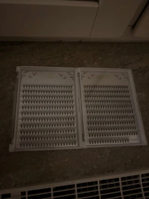 Individuella lösögonfransar Golden Unwinding - Två askar med individuella lösögonfransar i svart. Fransarna är organiserade i täta rader och har en naturlig, fjäderlik form. Perfekta för att bygga upp volym och längd efter eget önskemål. Förpackningen är vit med små hjärtan och blad som dekoration.