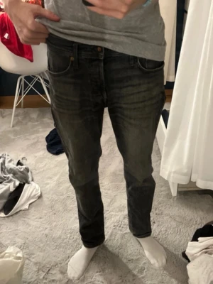 svarta jeans straight  - Säljer ett par svarta jeans med klassisk femficksdesign och diskret tvättad look. Jeansen har raka ben och normal passform. Perfekta till en avslappnad stil. Från Jack & Jones storlek 30/32.