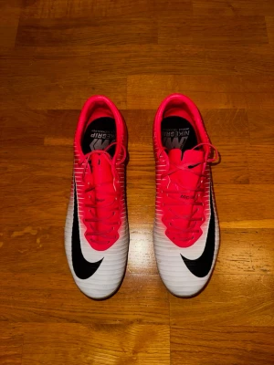 Nike Mercurial Vapor XI fotbollsskor röd/vit, stl 42 - Nike Mercurial Vapor XI fotbollsskor i en snygg röd och vit färg med svarta detaljer. Tillverkade i syntetmaterial för lätt känsla och bra grepp på planen. Perfekta för dig som vill sticka ut på fotbollsplanen. Storlek 42. Väldigt sparsamt använda. Otroligt eftertraktad sko. Priset är aningen förhandlingsbart. 