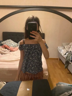 Blommig topp - Söt offshoulder topp med blommigt mönster i blått och vitt. Toppen har korta ärmar och en luftig passform.