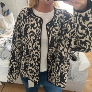 Svartvit quiltad bomberjacka med leopardmönster - Säljer en fett snygg quiltad bomberjacka från Zara med svart och beige leopardmönster. Jackan har rundad hals, lång ärm och svarta kantdetaljer. Perfekt att slänga över en t-shirt och jeans för en cool look.