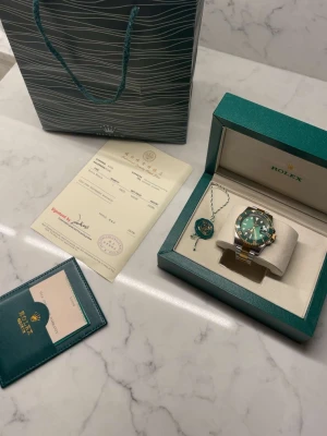 Klocka  - En väldigt fin klocka i färgen grön, silver och guld. Sprillans ny och väldigt stilig. 