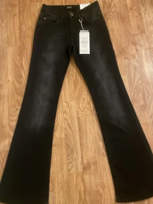 Svarta flared jeans med pärlor från ONLY - Svarta jeans från ONLY i modellen Blush Flared med midwaist. Byxorna har utsvängda ben och är dekorerade med små svarta pärlor på framsidan för en extra cool look. Materialet är klassisk jeans och de har fem fickor samt knapp och dragkedja.