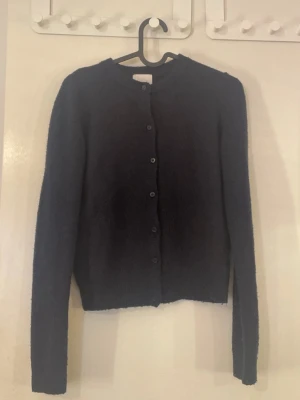 Mörkblå kofta från H&M - Säljer en mörkblå kofta från H&M med rund hals och knappar framtill. Koftan har lång ärm och är stickad i ett mjukt material som känns skönt mot huden. Inga defekter. 