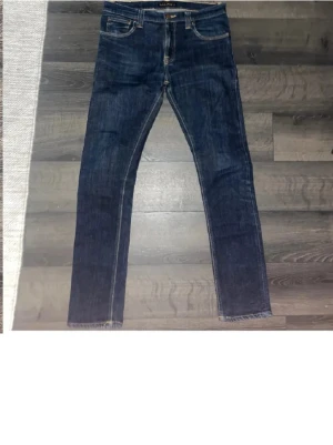 Nudie Jeans - Säljer ett par mörkblå  jeans från Nudie Jeans. Jeansen har normal passform. Perfekt för dig som gillar stilrena jeans. Passform Slim fit. Pris kan diskuteras vid snabb affär🤝