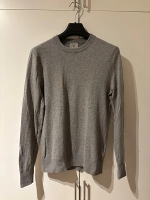 Grå cashmere-tröja från H&M - Säljer en grå tröja i cashmere från H&M i toppenskick. Den är väldigt mjuk, tunn och skön att bära och passar perfekt både till vardags och till mer uppklädda outfits. Tröjan är märkt storlek XS men är stor i storleken och sitter mer som en S. En stilren och tidlös tröja som är lätt att matcha med jeans eller chinos. Använd få gånger och i mycket fint skick.