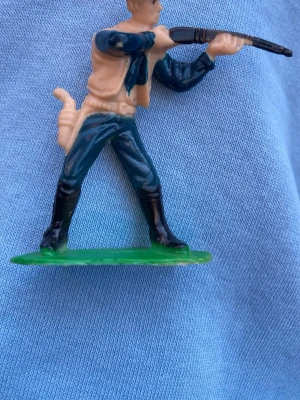 vintage plast cowboy western figur - Säljer en vintage cowboy i klassisk stil, perfekt för dig som gillar western-vibbar. Cowboy är stilig och unik med sin fina beiga väst, och rak passform. Materialet är slätt och känns som syntet. Passar till dig som vill sticka ut med en cool westernlook.