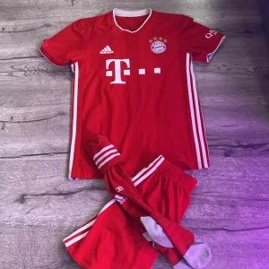 Bayern München Kimmich matchtröja Adidas S - Röd Bayern München fotbollströja från Adidas med Kimmich 32 på ryggen. Klassisk design med vita detaljer, klubbmärke och sponsortryck framtill. Tillverkad i ventilerande polyester med korta ärmar och V-ringning. Inkluderar matchande shorts och strumpor.