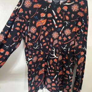 Mönstrad långärmad SQRTN - Säljer en långärmad tröja från SQRTN med färgglatt blommigt och paisleymönster i rött, orange och blått. Tröjan har rund halsringning och är perfekt för dig som gillar unika prints och bekväm stil. Knappt använd, som ny.