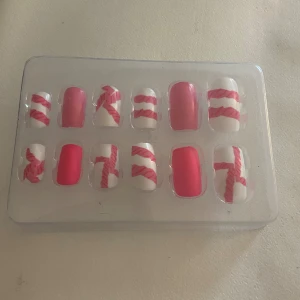 Rosa och vita lösnaglar med mönster - Säljer ett set med lösnaglar i rosa och vitt, vissa med coola ränder och snirkliga mönster i rosa på vit bakgrund.