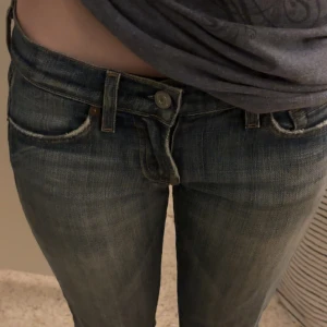 7 For All Mankind blå jeans, stl 25 - Snygga blå jeans från 7 For All Mankind med klassisk femficksdesign och låg midja. Aldrig använda men köpta secondhand. Jeansen har en lätt tvättad look och raka ben. Perfekta för dig som gillar en avslappnad men stilren vibe.