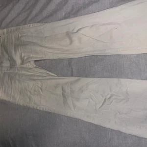 Beiga byxor från H&M, storlek 32 - Snygga beiga byxor från H&M i storlek 32. Klassisk femficksmodell med raka ben och normal passform. Tillverkade i mjuk bomull med diskreta sömmar och dragkedja framtill. Perfekta för en clean och stilren look.