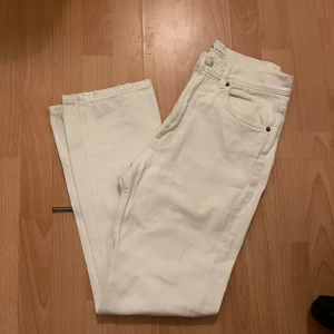 Vita raka jeans från Zara - Säljer ett par vita jeans från Zara med klassisk femficksdesign och raka ben. Jeansen har hög midja och är tillverkade i bomull för en skön och stilren look. Perfekta för dig som vill ha en clean vibe och matcha med allt. 