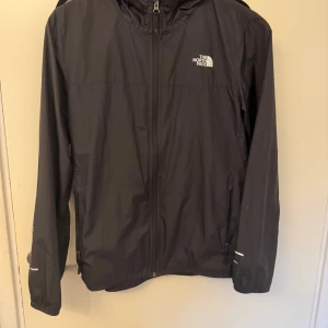 The North Face Vindjacka  - En vindjacka från The North Face. Jackan är i bra skick utan skador. Det är en barn storlek i xl men sitter perfekt på mig som är 180. Hör av er vid fler frågor