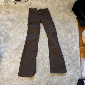 Bruna bootcut byxor med broderade fickor - Snygga bruna byxor med bootcut-modell och coola broderade detaljer på bakfickorna. Klassisk femficksdesign och låg midja. Perfekta för dig som gillar en retroinspirerad look med lite utsvängda ben.