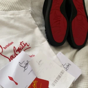  svarta sneakers - Svarta sneakers  med ikonisk röd sula och svarta nitar på tån.  Helt nya 