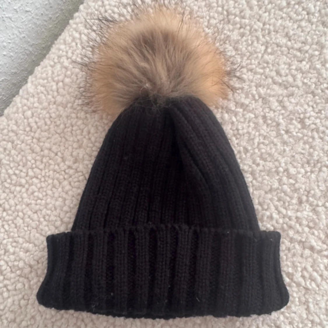 Svart ribbad mössa med pälsboll - 1