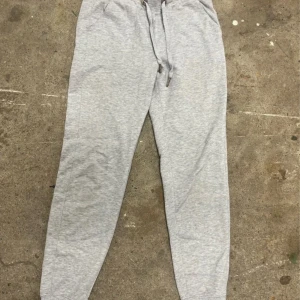 Grå mjukisbyxor från Amisu XS - Ljusgrå mjukisbyxor från Amisu i storlek XS. Byxorna har resår i midjan med snörning och är tillverkade i mjukt bomullsmaterial. Perfekta för chill dagar eller när du vill vara extra bekväm.
