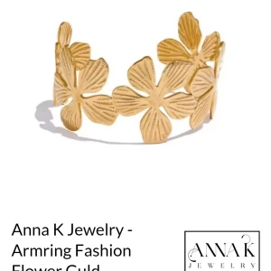 Guldigt blommigt armband Anna K Jewelry - Snyggt armband i guld från Anna K Jewelry med ett unikt blommigt mönster. Armbandet har öppet utförande och är dekorerat med flera detaljerade blommor som ger en cool och trendig vibe. Perfekt för dig som vill sticka ut med dina accessoarer.