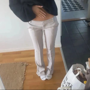 Ljusbeige Vera kostymbyxor bikbok - Snygga ljusbeige kostymbyxor med låg midja i modellen VERA från Bikbok. Helt oanvända med lappar kvar. Byxorna har pressveck, hällor för bälte och fickor både fram och bak. Perfekta för en clean och stilren look. 