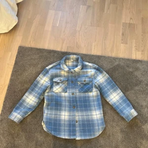 Blå och vit rutig fleece skjorta - Snygg overshirt i blått och vitt med rutigt mönster. Är i fleece.
