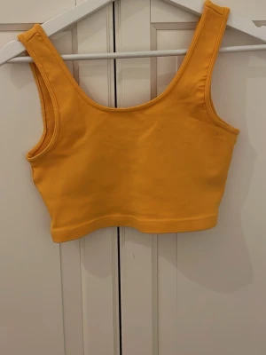 Gul croppad linnetopp Gina Tricot - Säljer en croppad linnetopp från Gina Tricot i en stark gul färg. Toppen har breda axelband och är tillverkad i mjuk bomull med stretch. Perfekt till sommaren och enkel att matcha med jeans eller kjol.