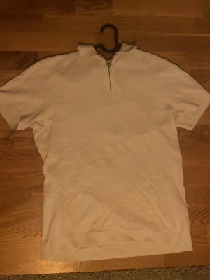 Vit kortärmad quarter zip - Säljer en somrig quarterzip tisha då den inte kommer till användning längre, mycket bra skick och använd endast ett fåtal gånger.