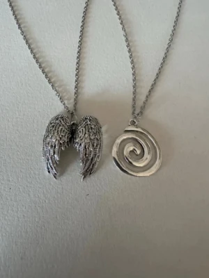 Silverhalsband x2 änglavingar + spiral - Säljer smycken som skapats som hobby av mig och dottern.   Halskedjan är ca 45-50cm  Bilder på berlock kan vara missvisande så är det viktigt så fråga gärna om mått 🌹  Smycken är inte av äkta guld/silver .   Inga bud godtas då priserna är så billiga❤️