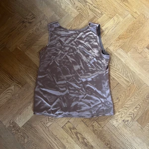 Champagnefärgad linnetopp By Malene Birger - Säljer en snygg champagnefärgad linnetopp från By Malene Birger. Toppen är ärmlös och har en slät, glansig satinfinish som ger en lyxig känsla. Perfekt att styla med jeans eller kjol för en trendig look.