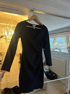 Marinblå omlottklänning från NY ONE - Snygg marinblå omlottklänning från NY ONE med lång ärm och v-ringad hals.