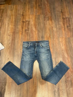 Jack & Jones Slim Fit Glenn Jeans - Snygga blå jeans från Jack & Jones i modellen Slim Fit Glenn. Jeansen har klassisk femficksdesign, medelblå tvätt och subtila slitningar för en cool look. Passformen är slim och materialet är mjukt jeans-tyg som sitter skönt hela dagen.