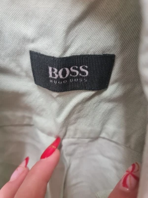 Ljusgrön skjorta från Hugo Boss - Snygg ljusgrön skjorta från Hugo Boss med klassisk krage och vita knappar framtill. Skjortan har lång ärm och ett diskret broderat B på bröstet. Materialet känns som bomull och ger en chill och fräsch vibe.