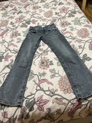 Bootcut jeans från Gina Tricot, grå - Säljer ett par grå bootcut jeans från Gina Tricot i storlek 146. Jeansen har två knappar fram, klassiska fickor både fram och bak samt en snygg tvättad look. Materialet är jeans och passformen är normal med lite utsvängda ben.