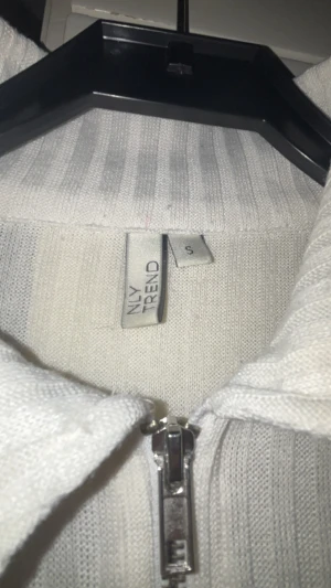 Vit ribbad zip-kofta från NLY Trend - Säljer en vit ribbad kofta från NLY Trend i storlek S. Tröjan har lång ärm, hög krage och dragkedja framtill. Materialet är mjukt och stickat, perfekt för lager på lager. Enkel och clean look som funkar till många stilar. Använt nån enstaka gång bara.