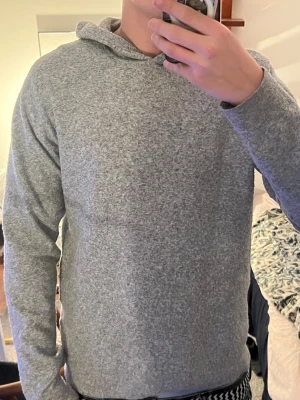 Grå hoodie med huva i stickad stil - Modellen är 184 cm lång och väger 72 kg‼️Mjuk och skön grå hoodie med huva, tillverkad i stickat material. Tröjan har långärmade ärmar och en enkel, clean design utan synliga detaljer eller mönster. Perfekt för chill dagar och passar dig som gillar basic och comfy plagg.