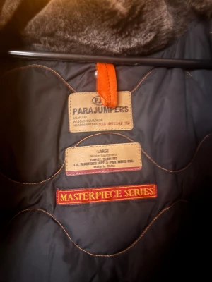 Parajumpers parkajacka L - Säljer en svart Parajumpers parkajacka med päls på huvan och ikonisk gul rem. Jackan har flera fickor, patch på ärmen, dragkedja och knappar framtill. Insidan är fodrad med mjuk syntetpäls för extra värme. Perfekt för kalla vinterdagar. Inga skador på varken dragkedjor,knappar eller tyg. Sparsamt använd, byten intressant