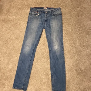 Blå Hilfiger Denim jeans 34/34 - Snygga blå jeans från Hilfiger Denim i klassisk straight fit. Jeansen har fem fickor, knappgylf och diskreta slitningar framtill för en cool look. Passar dig som gillar en tidlös stil med lite edge. Perfekt längd och midja för dig som vill ha en bekväm passform.