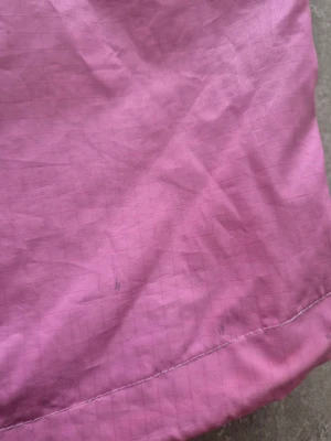 Vindjacka  - Säljer en rosa vindjacka.  Jackan har en klassisk passform och är tillverkad i syntetmaterial som känns smidigt och skyddar mot vind. Perfekt för dig som vill sticka ut med färg i vardagen.