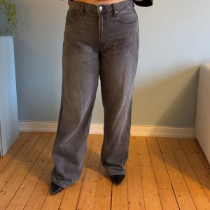 Gråa wide jeans med hög midja - Säljer ett par gråa jeans med hög midja och breda ben. Klassisk femficksmodell med knapp och dragkedja framtill. Jeansen har en avslappnad passform och är tillverkade i jeansmaterial. Perfekta för dig som gillar en loose och chill stil.