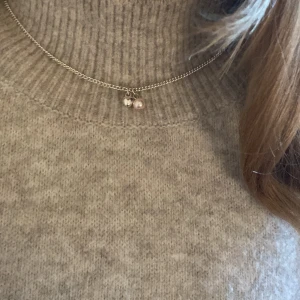 Silverhalsband med hjärta och pärla - Snyggt och stilrent halsband i silver med två berlocker – ett litet hjärta och en ljusrosa pärla. Kedjan är tunn och elegant, perfekt för att ge en subtil touch till din look. Passar dig som gillar enkla men fina detaljer.