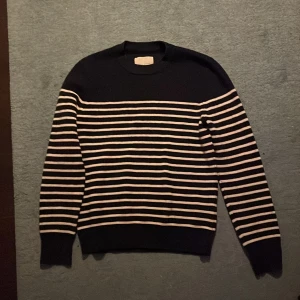 Randig svart stickad tröja Samsøe - Snygg svart stickad tröja från Samsøe Samsøe med vita horisontella ränder över hela kroppen och ärmarna. Rund hals och ribbade muddar vid ärmslut och nederkant. Perfekt för dig som gillar klassisk stil med en modern twist. Storlek M men liten i passformen skulle säga mer S. Priset är inte hugget i sten hör av dig!